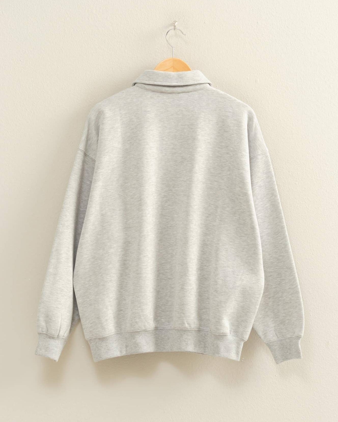 Gray sweater on a hanger against a beige wall